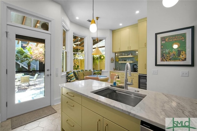 kitchen with pendant lighting, cream cabinetry, a wealth of natural light, and a sink