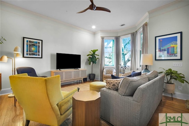 living area featuring visible vents, ornamental molding, and wood finished floors