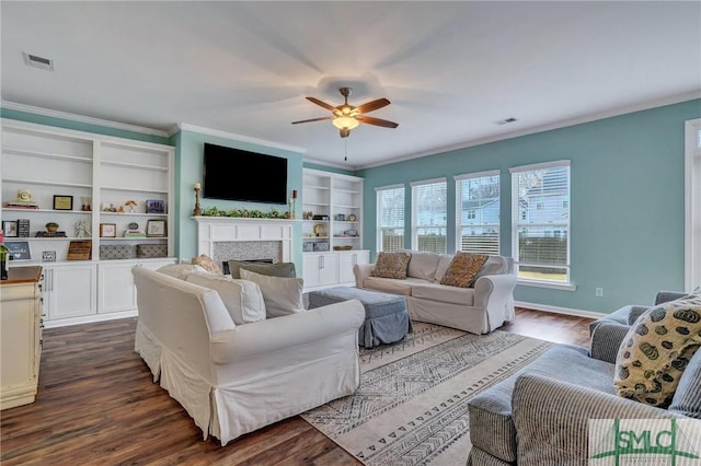 living room featuring visible vents, dark wood-type flooring, ornamental molding, a fireplace, and ceiling fan