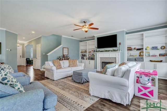 living area with ceiling fan, wood finished floors, a fireplace, and crown molding