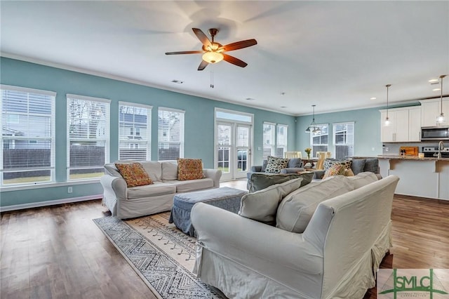 living room featuring baseboards, ceiling fan, ornamental molding, recessed lighting, and wood finished floors