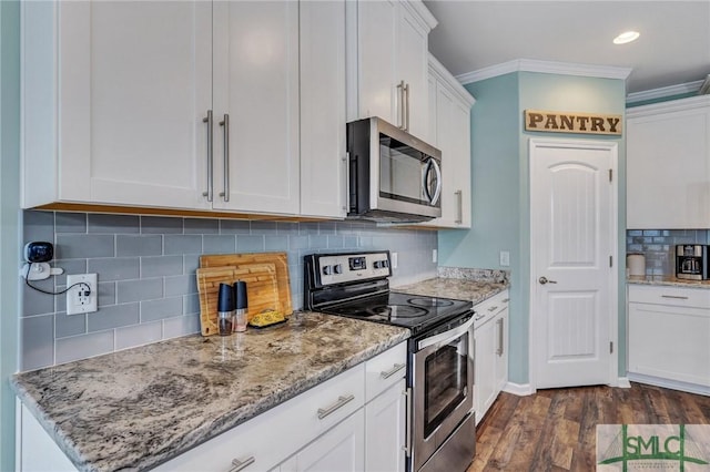 kitchen with light stone counters, dark wood-style floors, ornamental molding, stainless steel appliances, and white cabinets