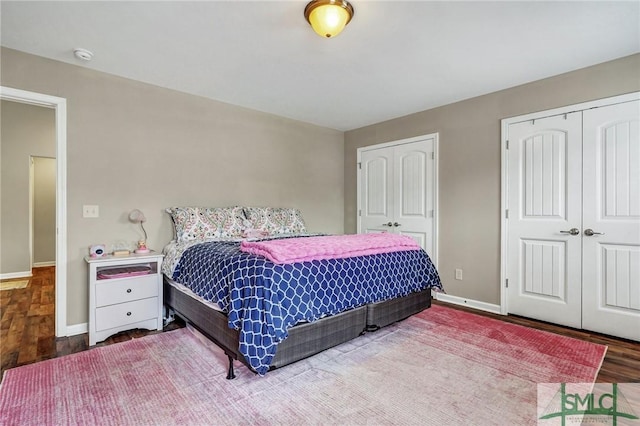 bedroom featuring two closets, baseboards, and wood finished floors