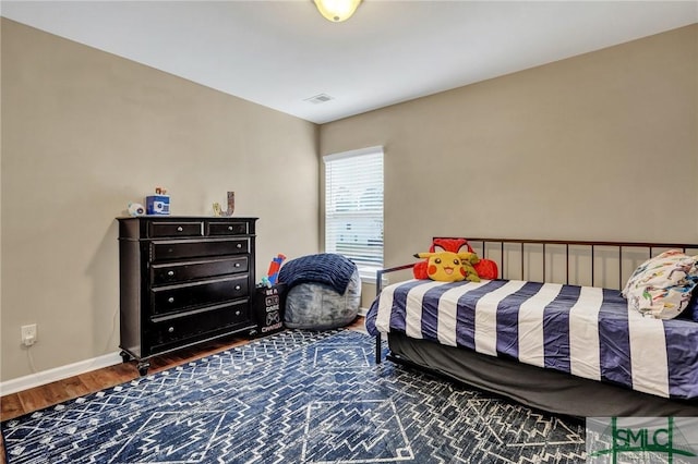 bedroom with visible vents, baseboards, and wood finished floors