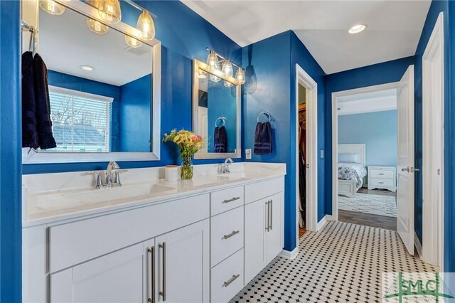 ensuite bathroom featuring double vanity, baseboards, ensuite bathroom, and a sink