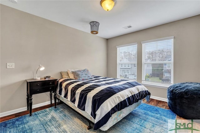 bedroom featuring visible vents, baseboards, and wood finished floors