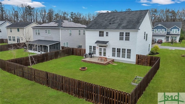 rear view of property with a yard, a fenced backyard, and an outdoor fire pit