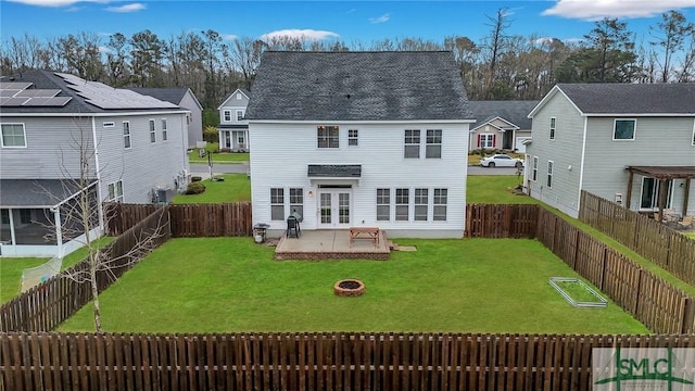 rear view of property featuring a patio area, a lawn, a fenced backyard, and an outdoor fire pit