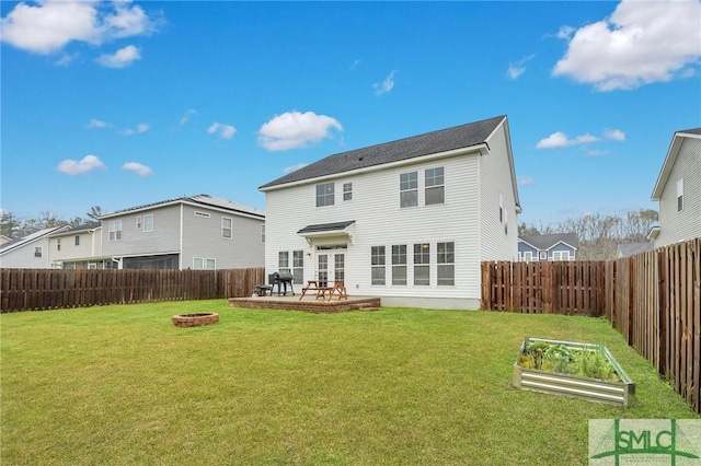 back of house featuring a fenced backyard, a lawn, a fire pit, and a vegetable garden