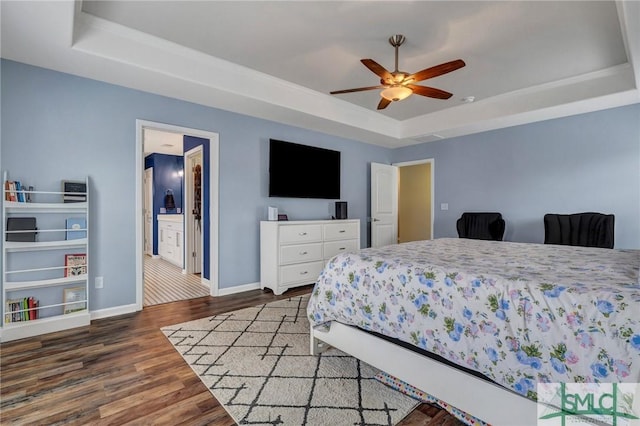 bedroom with a ceiling fan, a raised ceiling, baseboards, and wood finished floors