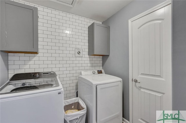 laundry area with tile walls, washing machine and dryer, cabinet space, and a sink