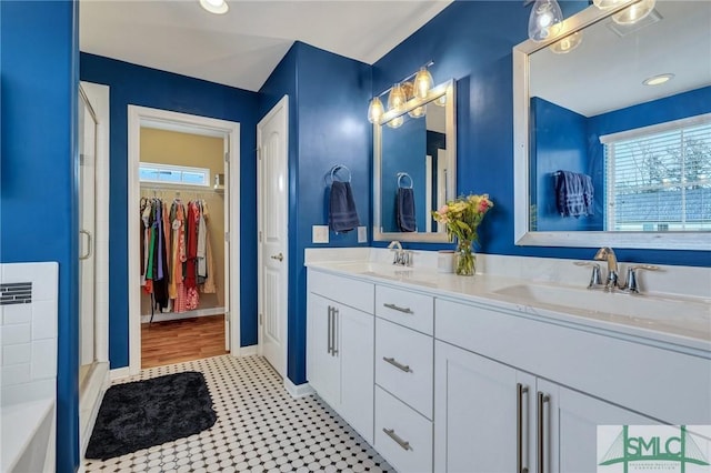 bathroom featuring a sink, a spacious closet, double vanity, and a shower stall