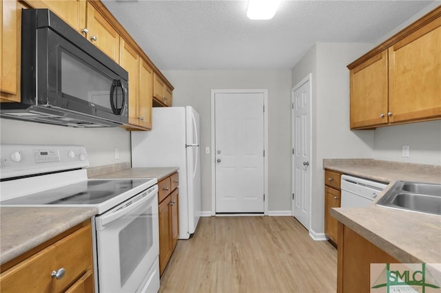 kitchen with white appliances, brown cabinetry, light wood-style flooring, light countertops, and a textured ceiling