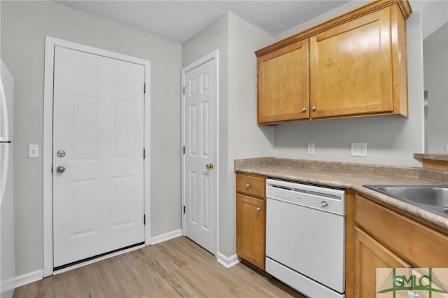 kitchen featuring light countertops, baseboards, white dishwasher, and light wood-type flooring