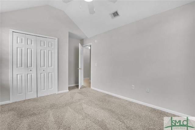 unfurnished bedroom featuring visible vents, a closet, carpet flooring, baseboards, and vaulted ceiling