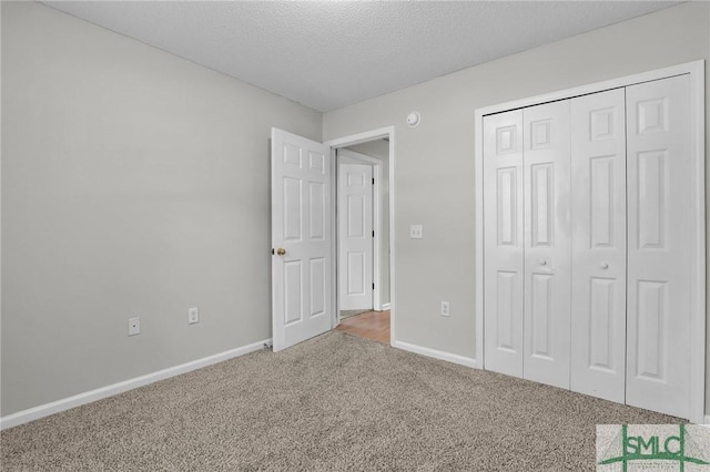 unfurnished bedroom featuring a closet, a textured ceiling, baseboards, and carpet floors