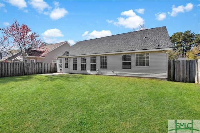 back of house featuring a lawn, a fenced backyard, and a shingled roof