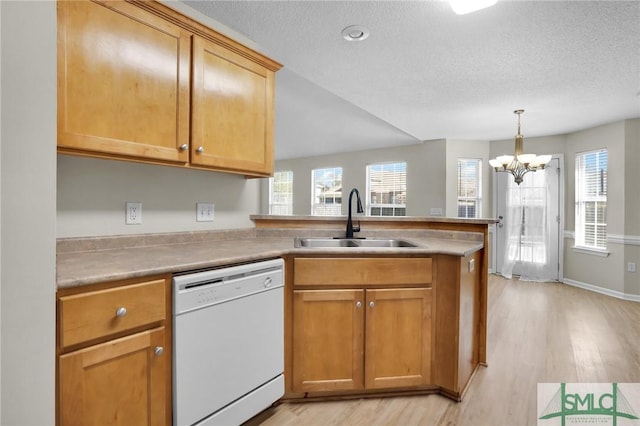 kitchen featuring light wood-style flooring, a sink, a textured ceiling, a peninsula, and dishwasher