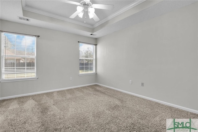 empty room with visible vents, carpet, a tray ceiling, and ornamental molding