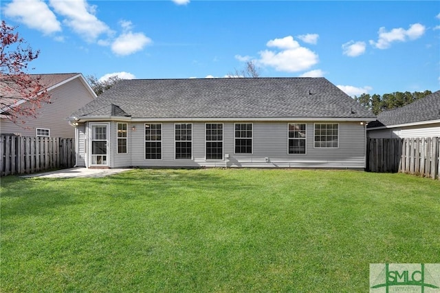 back of property with a fenced backyard, a patio, a yard, and roof with shingles