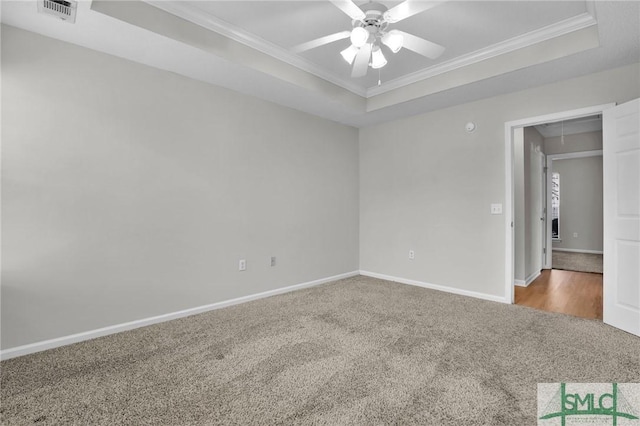 unfurnished bedroom featuring visible vents, carpet flooring, attic access, and a tray ceiling