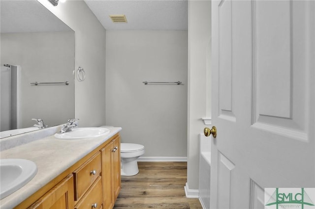 bathroom with a sink, visible vents, toilet, and wood finished floors