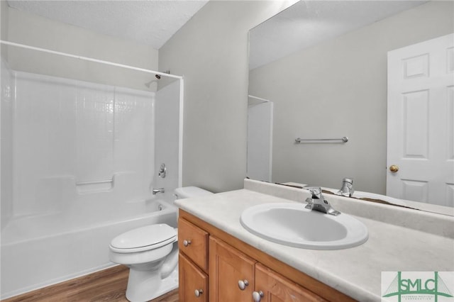 full bathroom with vanity, wood finished floors, a textured ceiling, toilet, and shower / bathtub combination