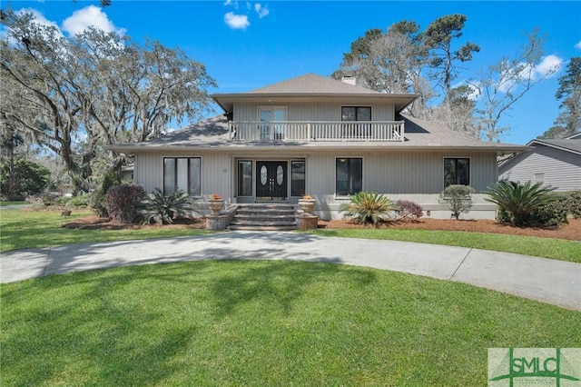 view of front facade featuring a front lawn, a balcony, and driveway