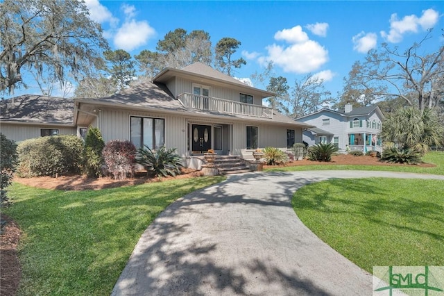 view of front of property featuring a front lawn, a balcony, and concrete driveway