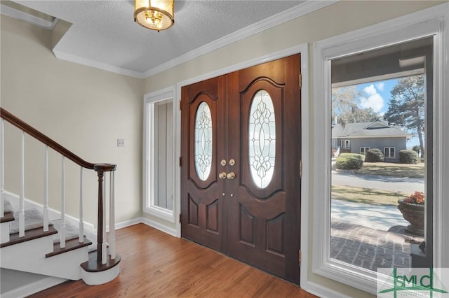 entryway featuring stairway, a textured ceiling, a healthy amount of sunlight, and wood finished floors