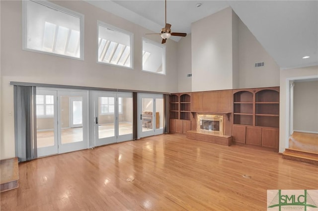 unfurnished living room featuring ceiling fan, a premium fireplace, and light wood-style flooring