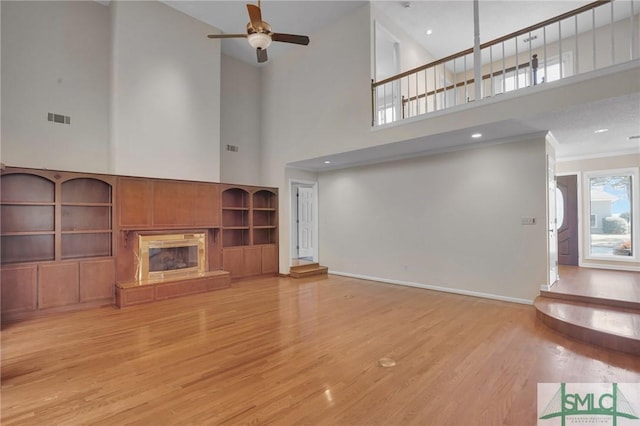 unfurnished living room featuring visible vents, ceiling fan, ornamental molding, a fireplace, and light wood-style floors