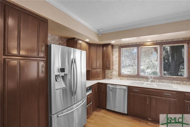 kitchen featuring a sink, stainless steel appliances, light wood-type flooring, and light countertops