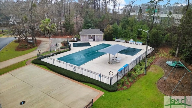 community pool with a patio, a yard, fence, and an outbuilding