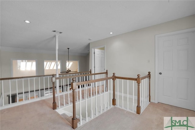 hallway with visible vents, an upstairs landing, a textured ceiling, recessed lighting, and carpet floors