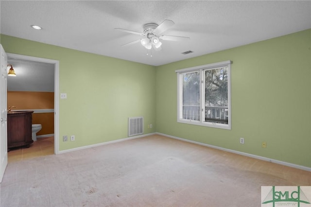 unfurnished bedroom featuring ensuite bath, baseboards, visible vents, and carpet floors