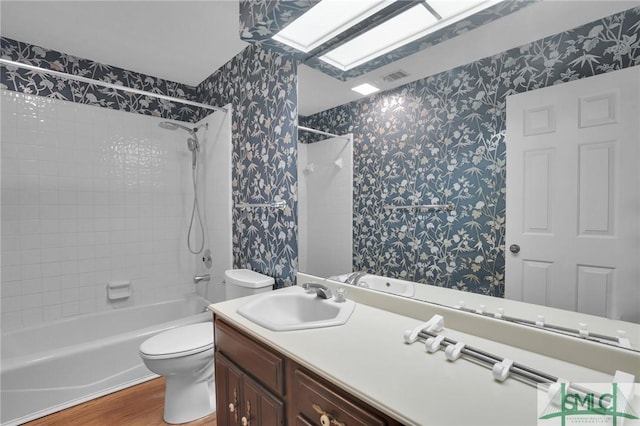 full bathroom featuring visible vents, toilet, a skylight, and wallpapered walls