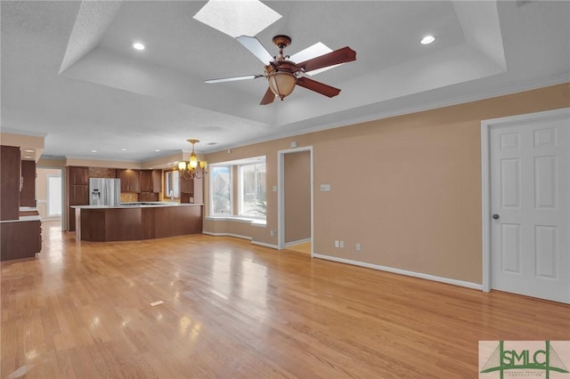 unfurnished living room featuring light wood finished floors, baseboards, and a tray ceiling