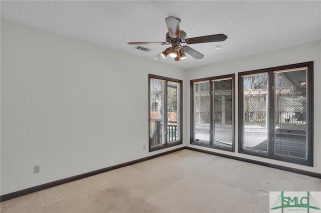 empty room with light colored carpet, visible vents, baseboards, and a textured ceiling