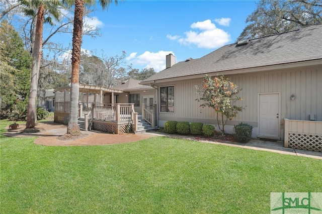 rear view of property featuring a wooden deck, a lawn, a chimney, and a pergola