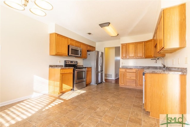 kitchen with visible vents, a sink, stainless steel appliances, baseboards, and light stone countertops