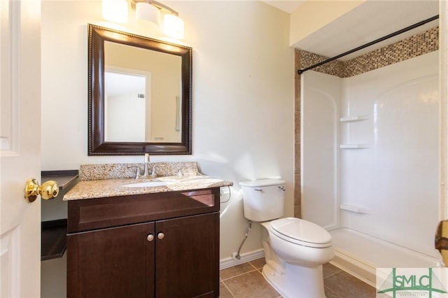 bathroom featuring tile patterned floors, vanity, toilet, and a shower