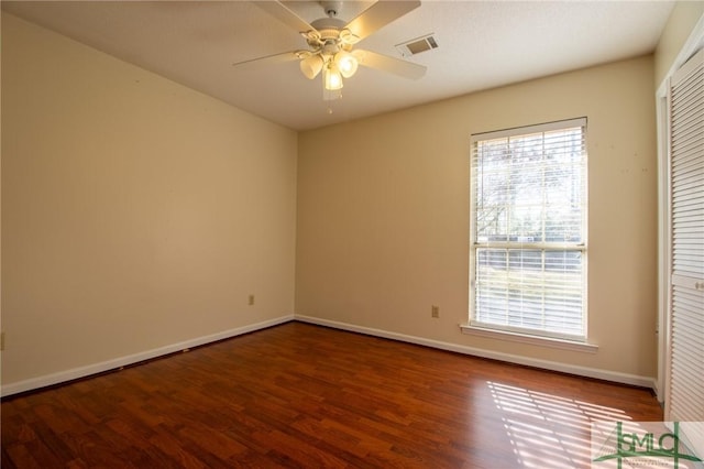 empty room with a ceiling fan, wood finished floors, visible vents, and baseboards