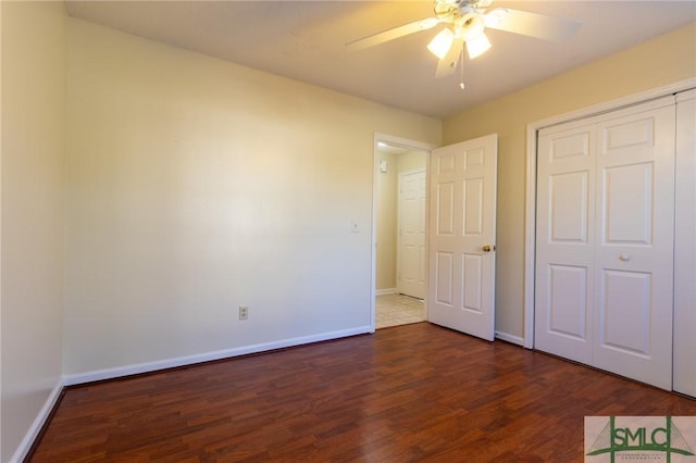 unfurnished bedroom with baseboards, dark wood-style flooring, a closet, and ceiling fan