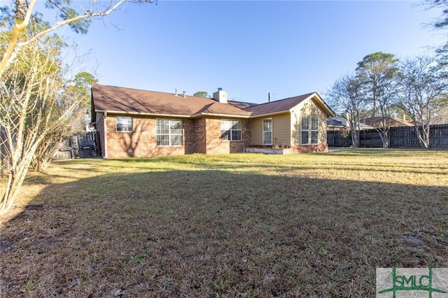 view of front facade featuring brick siding, a chimney, a front lawn, and fence