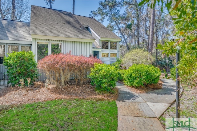 view of side of property with fence and roof with shingles