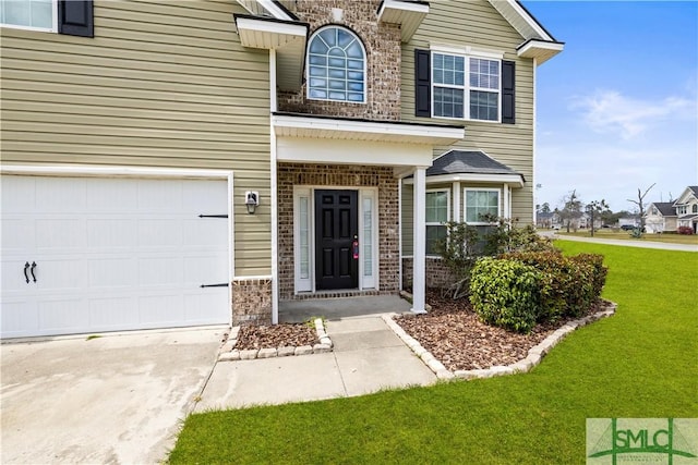 entrance to property featuring brick siding, a lawn, driveway, and a garage