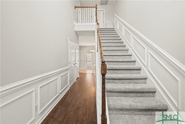 staircase featuring wood finished floors and a decorative wall