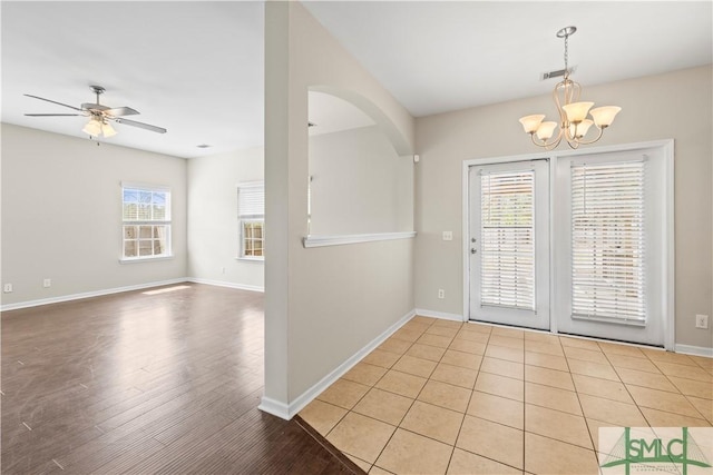 interior space with visible vents, ceiling fan with notable chandelier, light wood-style flooring, and baseboards