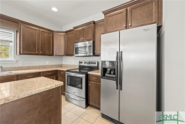 kitchen with dark brown cabinets, light tile patterned floors, recessed lighting, appliances with stainless steel finishes, and a sink